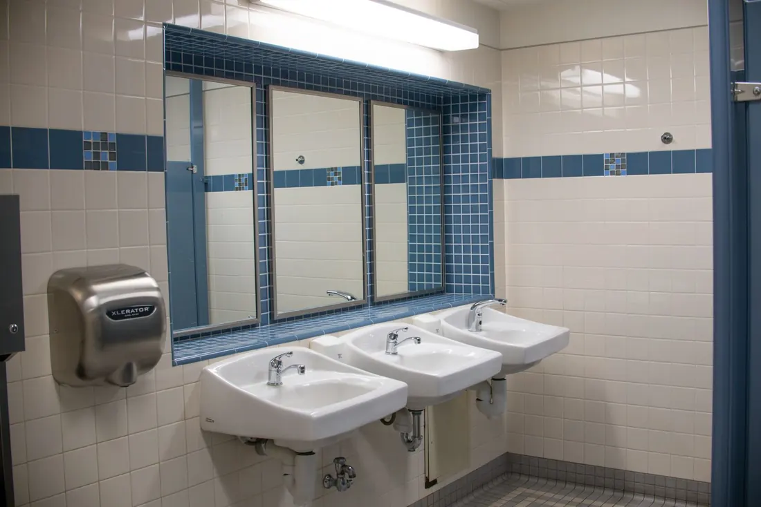 Commercial washroom with the sinks, mirrors and dryer wiped down